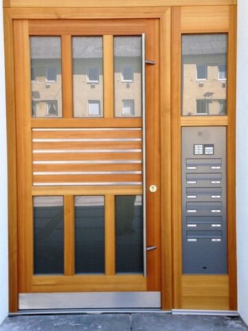 Haustüre in Lärche mit Edelstahl-Lisenen und Briefkastenanlage